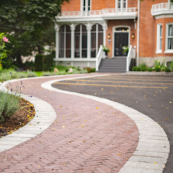 A close up view of interlocking leading up to a brick gothic revival house