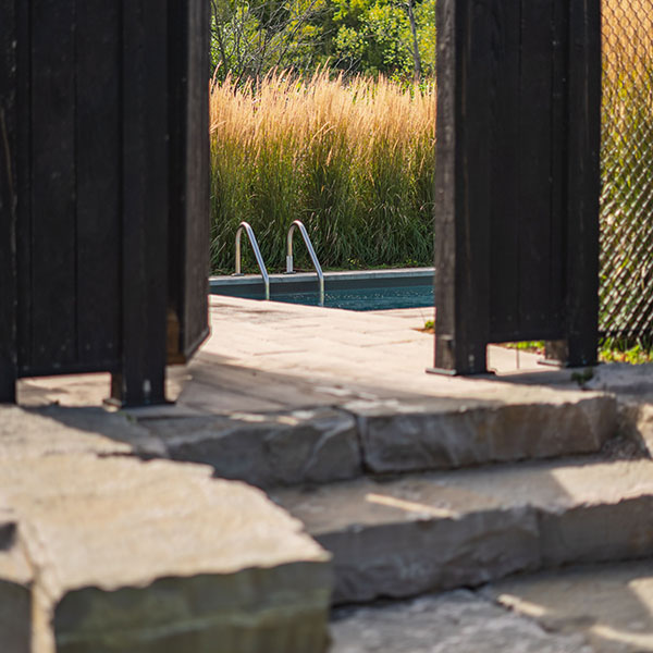 Close up view of stone steps that lead through a wooden fence to a pool